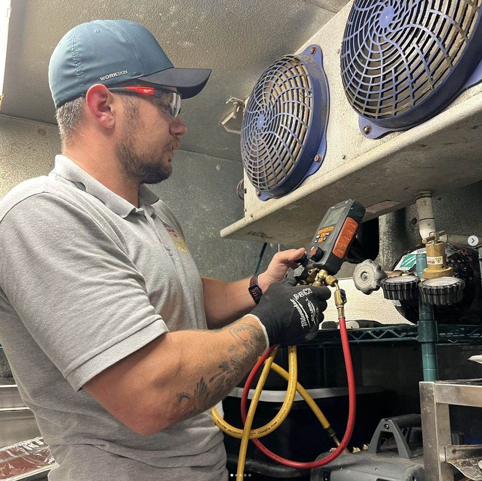 Technician checking refrigeration equipment with gauges