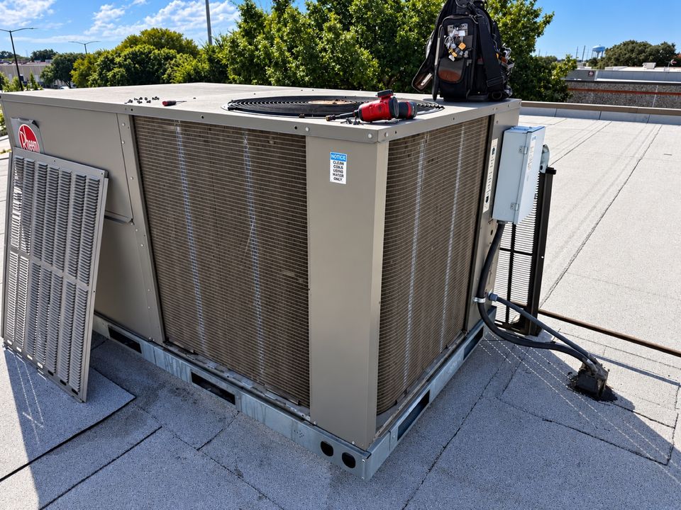 Technician working on a rooftop package unit on top of a commercial building