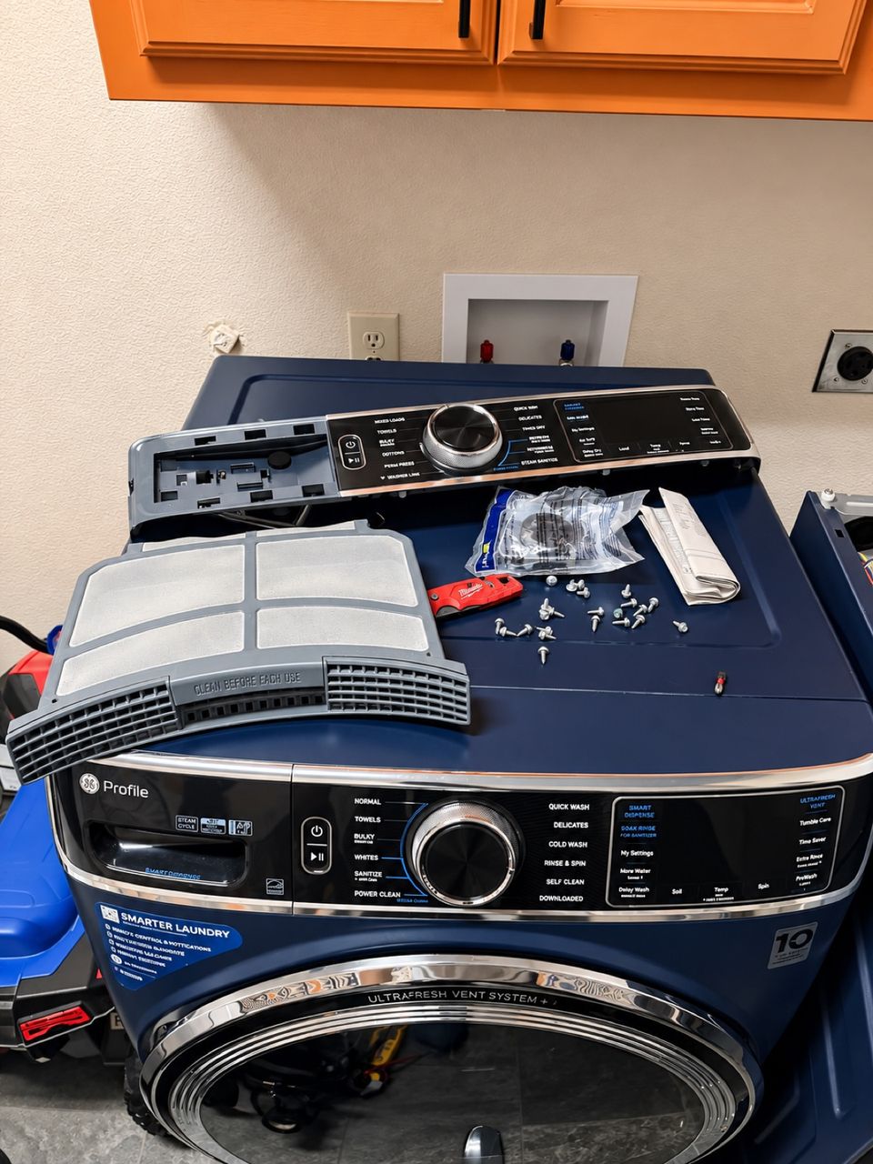 GE Profile front-load washer in a Frisco laundry room with a loose control panel, a lint screen and screws laid on top during a SmartWay repair