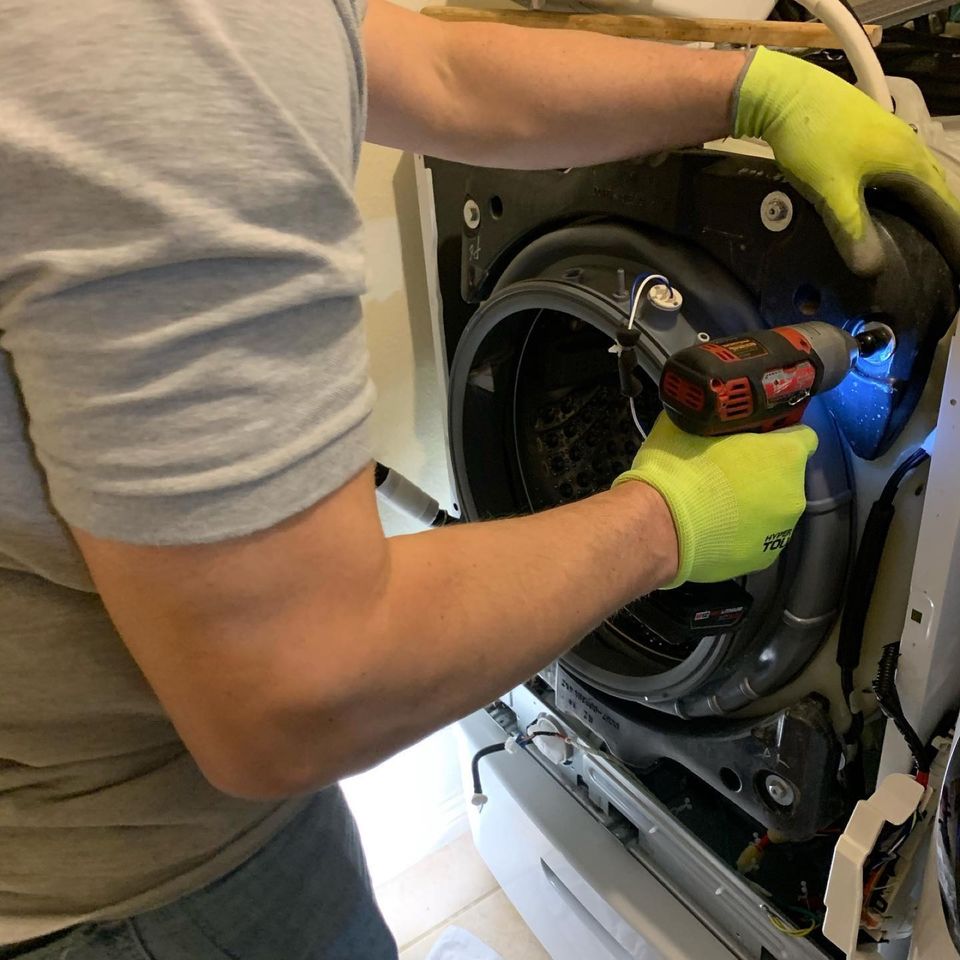 Technician in gloves working inside an open front-load washer